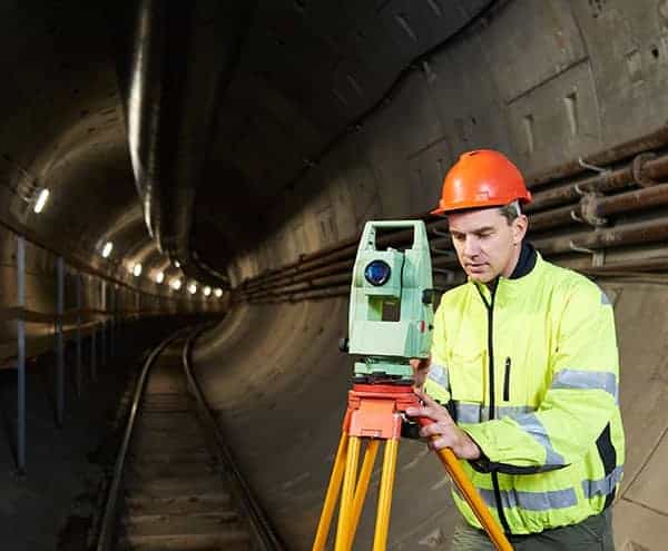 Railway surveyor with theodolite level at underground railway tunnel construction work