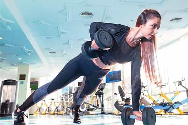 Female personal trainer lifting arm weight from plank position