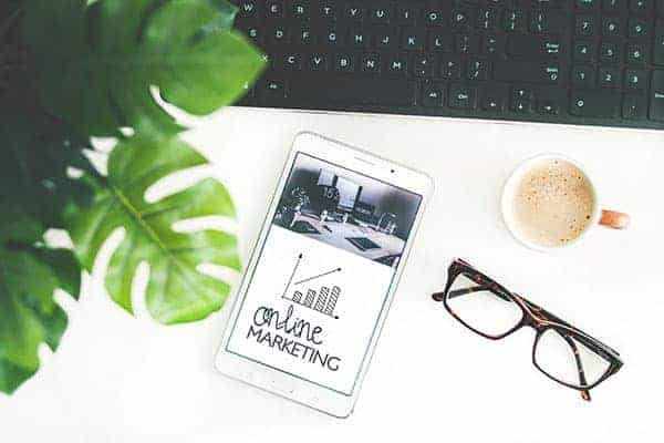 Business New Year's Resolutions - iphone being used for online marketing, glasses, coffee and keyboard on table