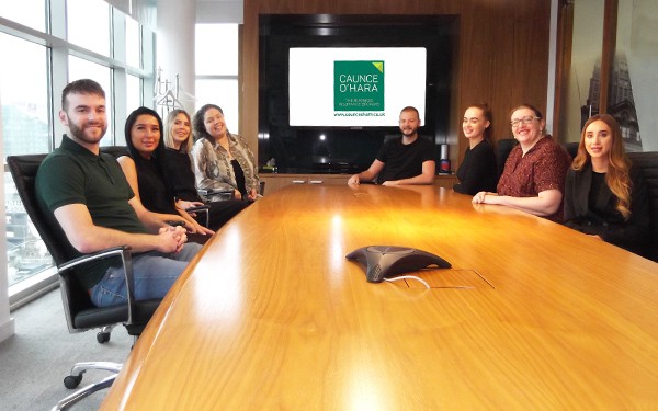 The Caunce O'Hara Schemes team sat around a boardroom table.