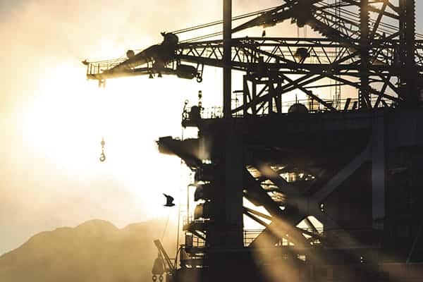 Sun shining in the background of an oil rig and crane