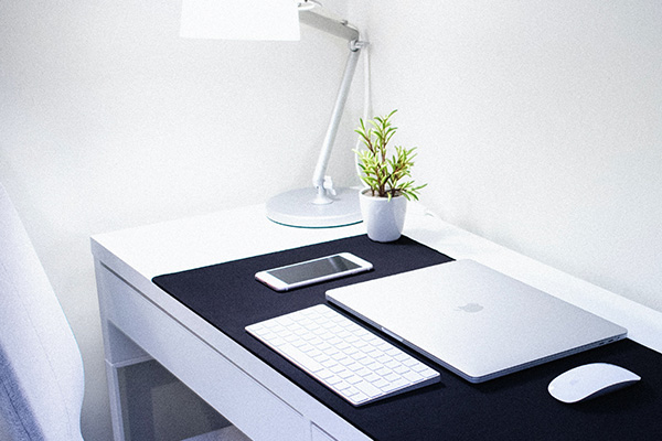 Laptop, keyboard and phone laid on desk in home office