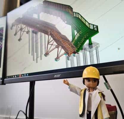 A female engineer barbie known as a 'Lottie Doll' in front of a computer screen