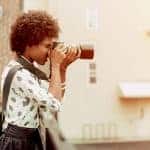 a freelance photographer taking a photo of a cityscape on her camera