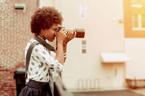 a freelance photographer taking a photo of a cityscape on her camera