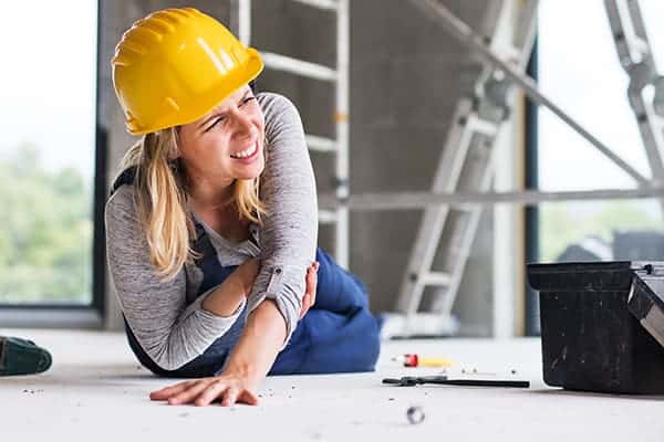 construction worker sitting on the ground holding arm following an injury