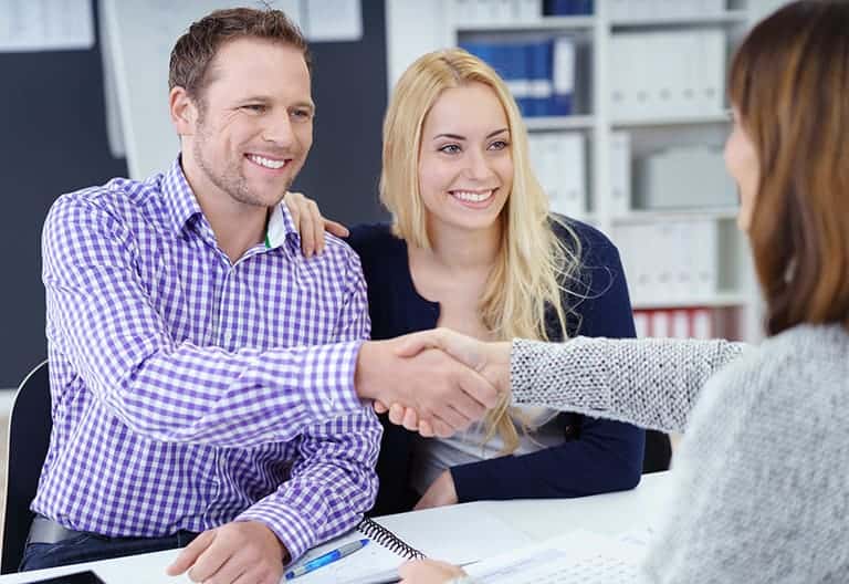 Couple with estate agent agreeing to buy a property