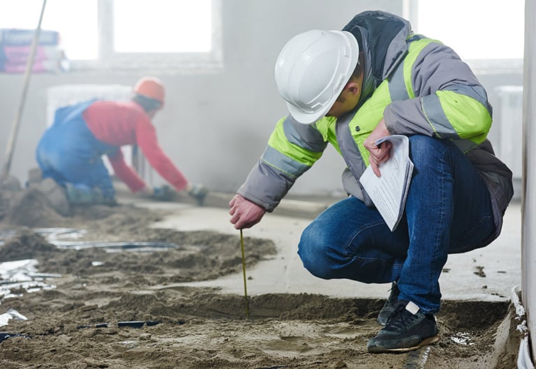 Builder measuring the depth of a floor screed