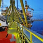 Offshore energy contractor insurance - The back of an offshore energy worker walking on to his work site in the evening.