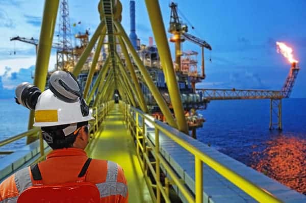 Offshore energy contractor insurance - The back of an offshore energy worker walking on to his work site in the evening.