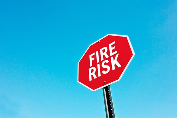 a red octagonal road sign with the words ‘fire risk’ in white in the middle